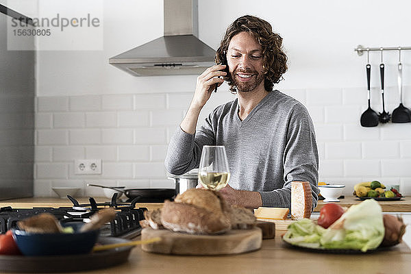 Mann am Telefon in der Küche zu Hause