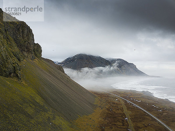 Island  Leere Straße zwischen rauen Bergen und dem Ufer des Jokulsarlon