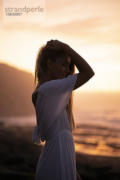 Junge Frau bei Sonnenaufgang am Strand