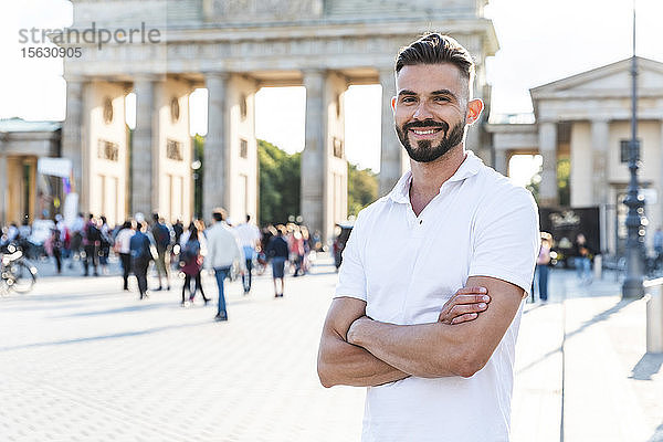 Porträt eines lächelnden jungen Mannes vor dem Brandenburger Tor  Berlin  Deutschland