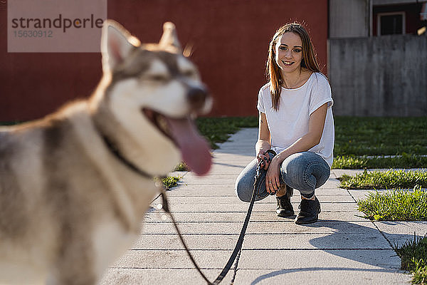 Porträt einer glücklichen jungen Frau mit ihrem Hund am Abend