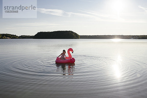 Mädchen mit Flamingo-Pool schwimmt auf einem See