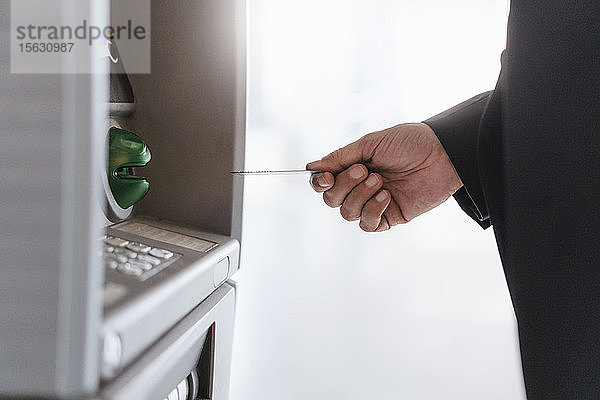 Nahaufnahme eines Geschäftsmannes  der Geld an einem Geldautomaten abhebt
