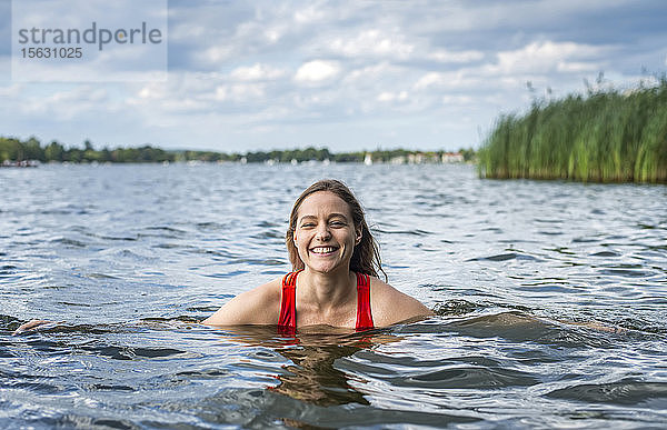 Porträt einer lächelnden Frau beim Baden in einem See