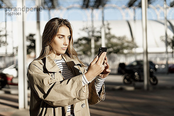 Junge blonde Frau  die ein Smartphone benutzt und ein Selfie
