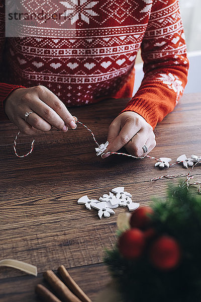 Frau macht Weihnachtsgirlande aus einem weißen Holzengel