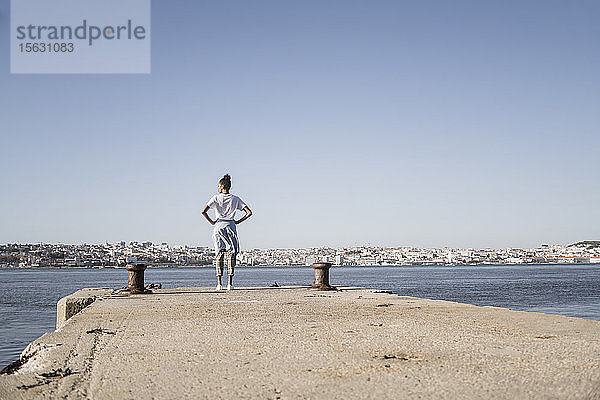 Junge Frau steht am Pier am Wasser  Lissabon  Portugal