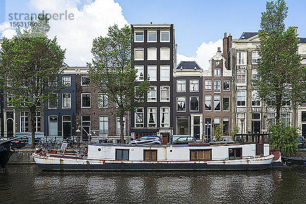 Niederlande  Amsterdam  Kahn am Rand des Stadtkanals vertäut mit Häuserzeile im Hintergrund