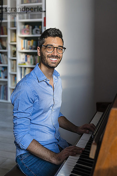 Porträt eines glücklichen jungen Mannes  der zu Hause Klavier spielt
