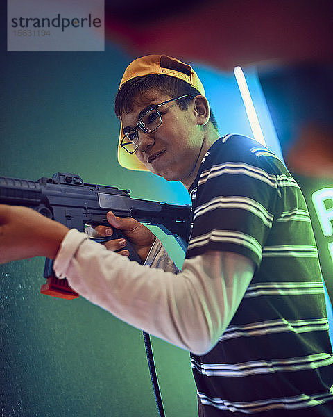 Teenager  der in einer Spielhalle mit einer Waffe schießt