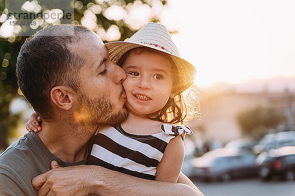 Vater küsst seine kleine Tochter bei Sonnenuntergang
