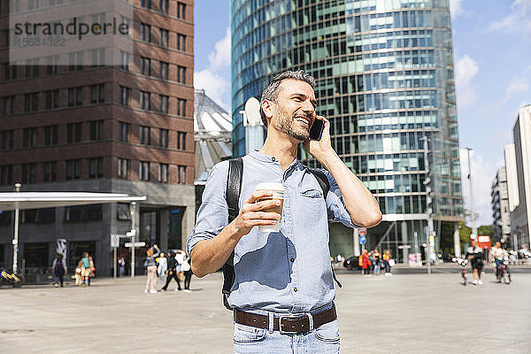Lächelnder Geschäftsmann beim Telefonieren in der Stadt  Berlin  Deutschland