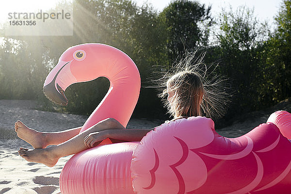 Mädchen sitzt auf einem Flamingo-Poolwagen