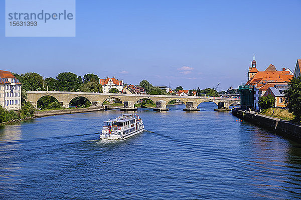 Ausflugsschiff auf der Donau mit der Steinernen Brücke im Hintergrund gegen den Himmel  Regensburg  Oberpfalz  Bayern  Deutschland