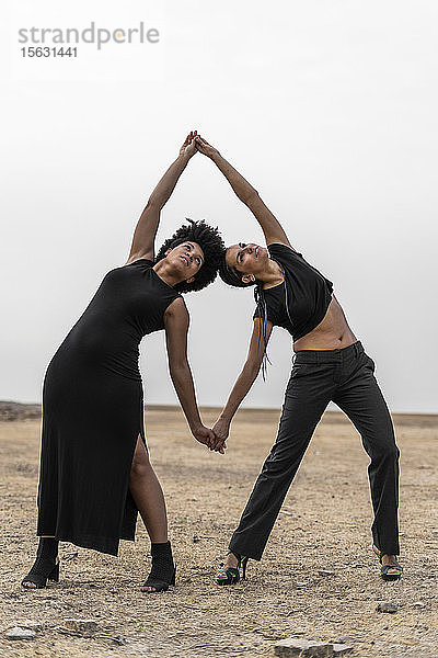 Zwei schwarz gekleidete Frauen treten in trostloser Landschaft auf