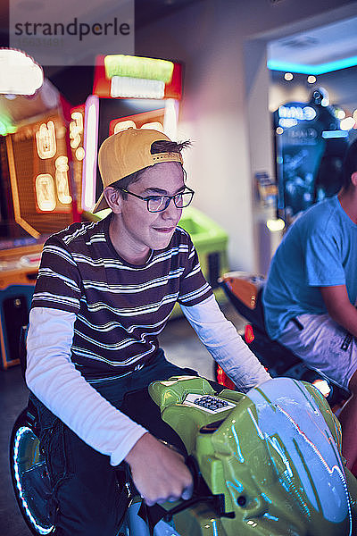 Teenager  der mit einem Fahrsimulator in einer Spielhalle spielt