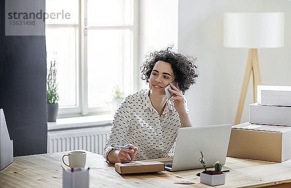 Lächelnde junge Frau am Telefon im Home-Office