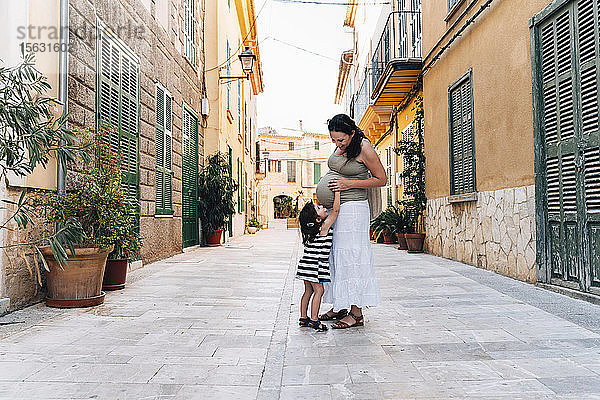 Kleines Mädchen berührt den Babybauch ihrer Mutter  Alcudia  Mallorca  Spanien
