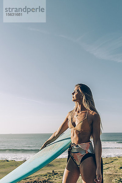 Junge blonde Surferin genießt das Sonnenlicht am Strand von Sopelana  Spanien
