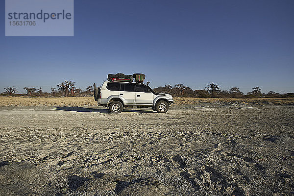 Weißer Geländewagen mit Affenbrotbäumen im Hintergrund vor klarem Himmel  Makgadikgadi Pans  Botswana