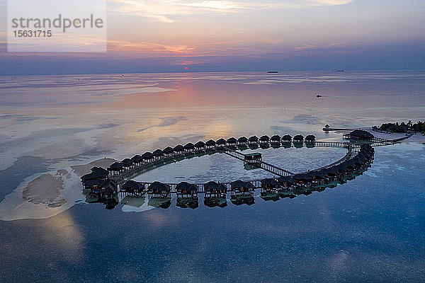 Luftaufnahme von Stelzenhäusern auf der Insel Olhuveli bei Sonnenaufgang auf den Malediven