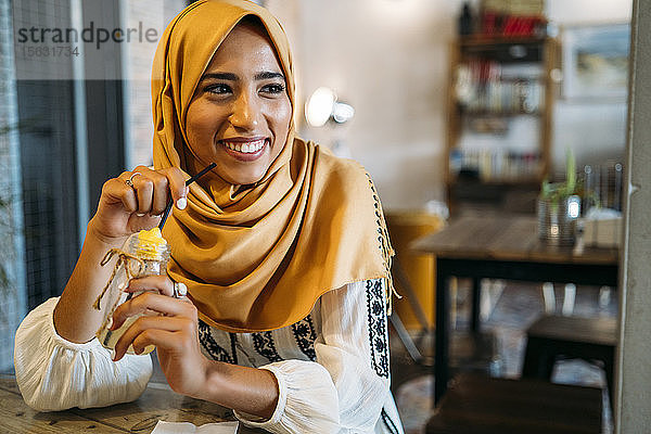 Junge muslimische Frau mit gelbem Hidschab in einem Café