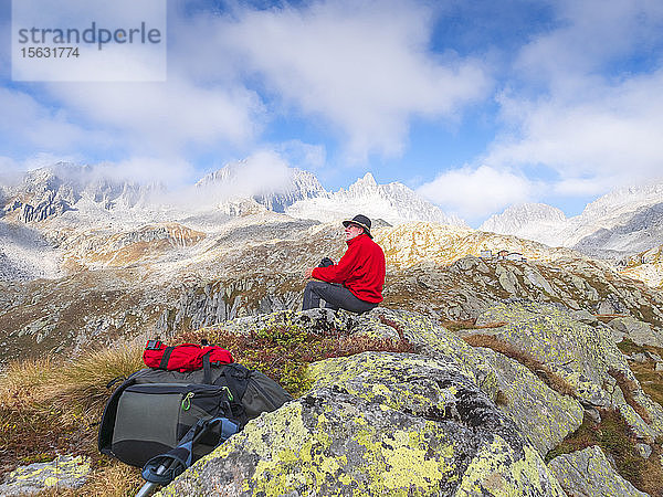 Wanderer sitzt auf einem Berg und geniesst die Aussicht  Naturpark Adamello  Italien