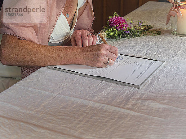 Braut unterzeichnet Dokument im Standesamt