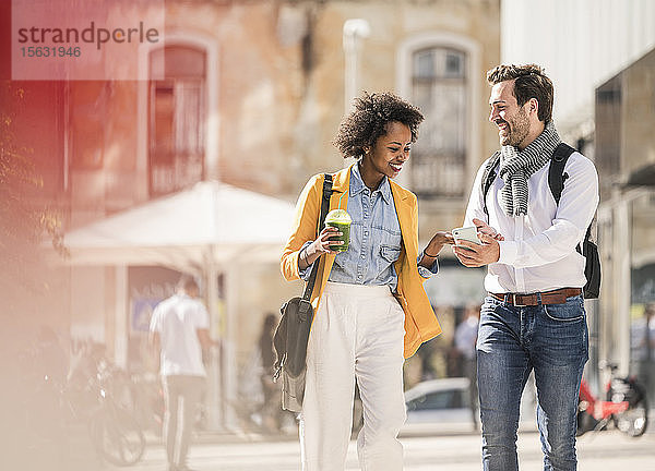 Glückliches junges Paar mit Smartphone in der Stadt