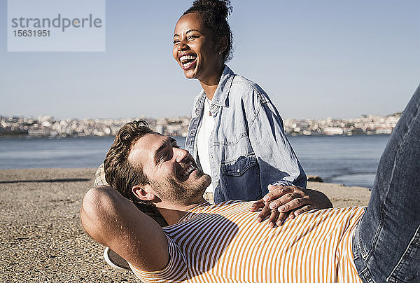 Glückliches junges Paar am Pier am Wasser liegend  Lissabon  Portugal