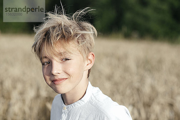 Porträt eines lächelnden blonden Jungen in einem Haferfeld