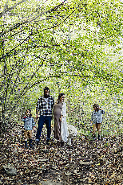 Familie mit zwei Kindern und Hund im Wald