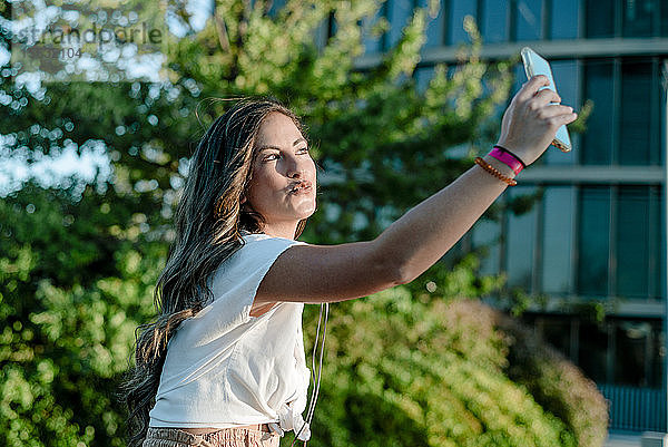 Junge Frau  die mit ihrem Smartphone einen Selfie macht und schmollt