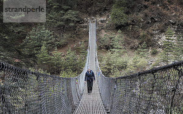 Junge Frau überquert die Phakdinger Suspensio-Brücke  Solo Khumbu  Nepal