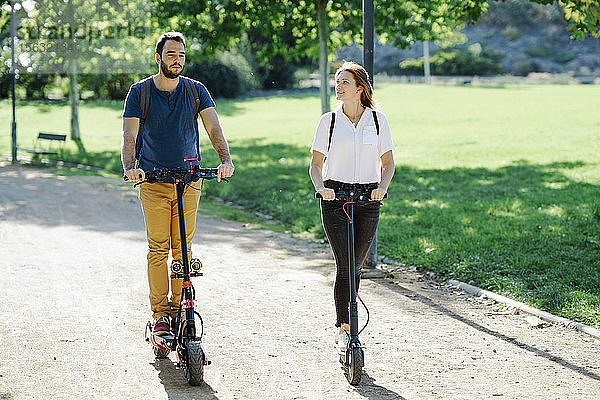 Ehepaar fährt Elektroroller in einem Stadtpark