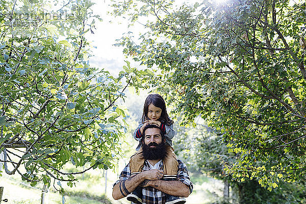 Porträt eines Vaters mit Kind auf den Schultern in einem Obstgarten