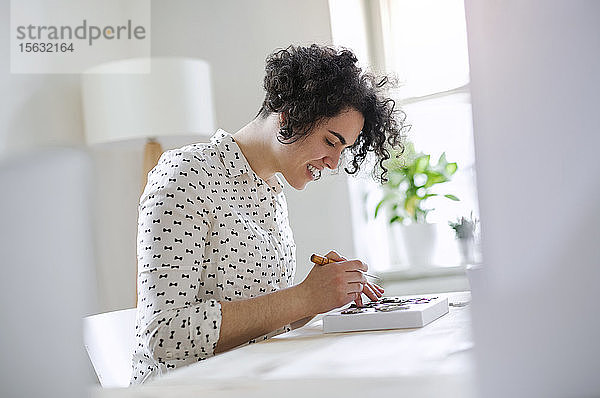 Lächelnde junge Frau bei der Arbeit am Tisch