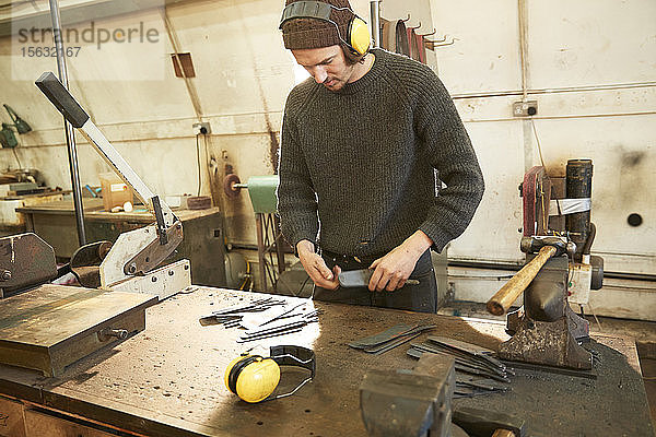 Mann macht Messer in einer Werkstatt