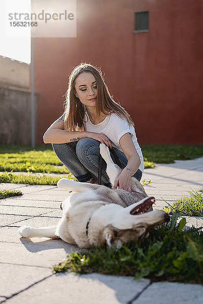Porträt einer jungen Frau  die abends ihren Hund im Freien streichelt
