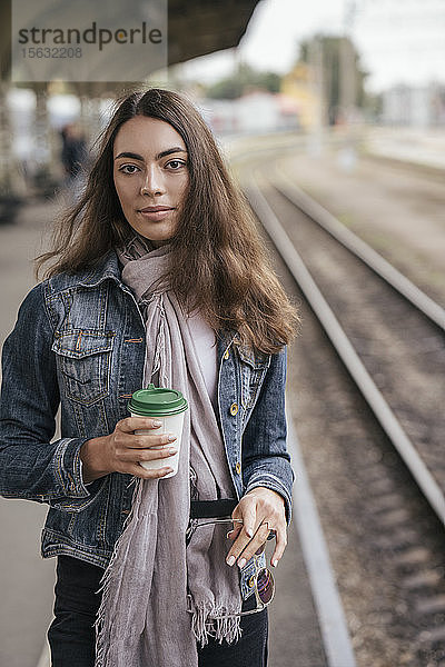 Junge weibliche Reisende mit Kaffee zum Bahnhof