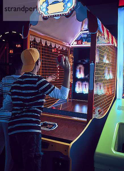 Teenager-Freunde werfen Bälle an einem Spielautomaten in einer Spielhalle