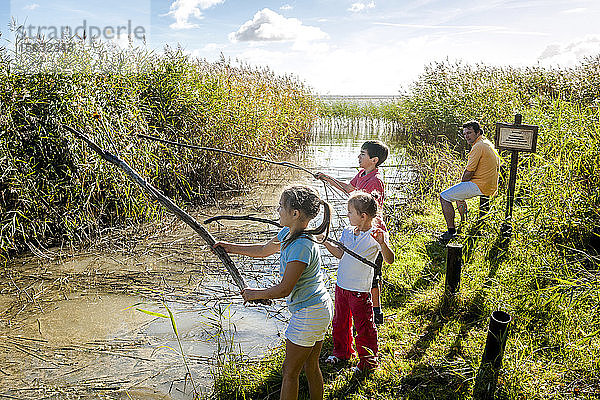 Kinder spielen mit Holzstöcken am Wasserlauf  Darß  Mecklenburg-Vorpommern  Deutschland