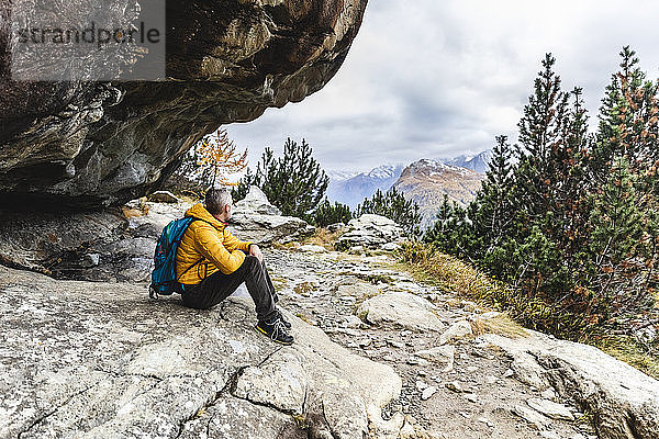 Wanderer sitzt und blickt im Herbst über das Alpenplateau  Sondrio  Italien