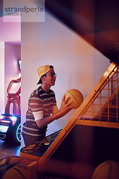 Teenager  der in einer Spielhalle Basketball spielt