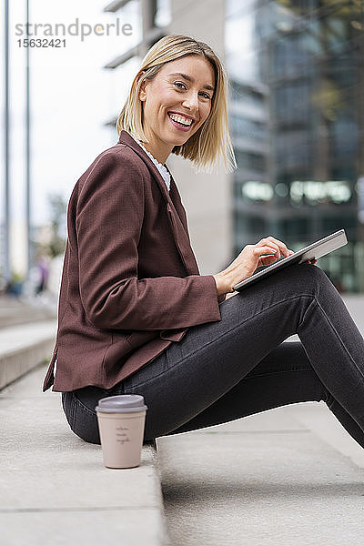 Porträt einer glücklichen jungen Geschäftsfrau mit Tablette in der Stadt