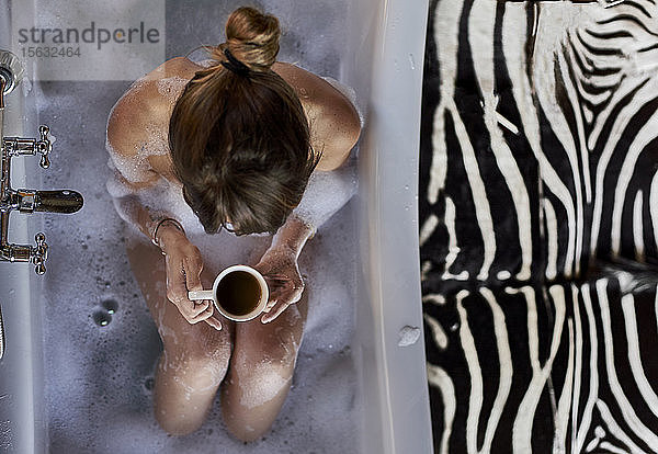 Frau bei einem entspannenden Bad und einer Tasse Kaffee in der Badewanne