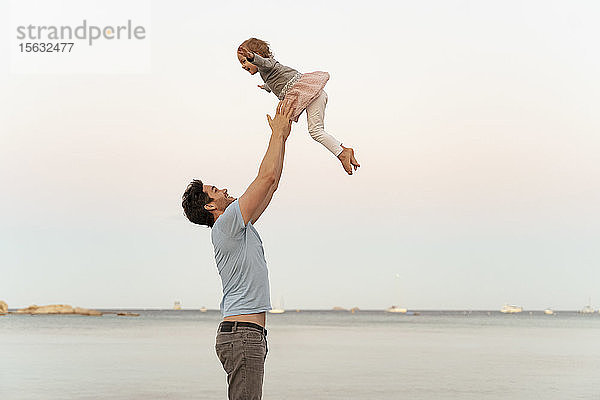 Glücklicher Vater wirft Tochter an den Strand