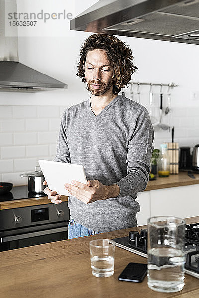 Mann benutzt Tablette in der Küche zu Hause