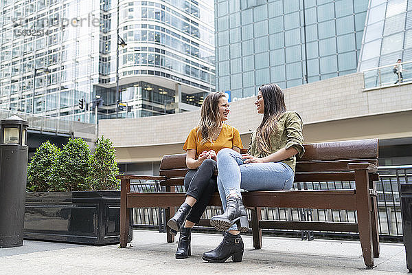 Glückliches lesbisches Paar sitzt auf einer Bank in der Stadt  London  UK