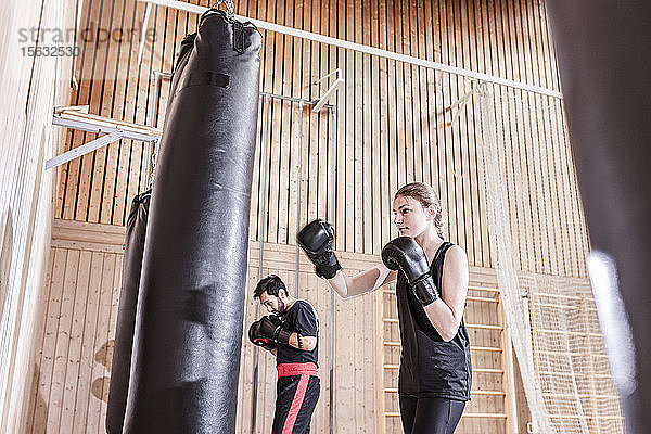 Trainerin und Boxerin beim Boxsacktraining in der Sporthalle